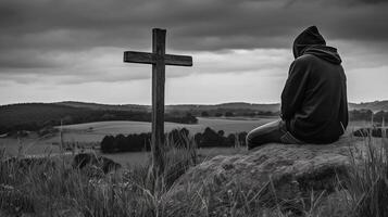 Man in front of a wooden cross in the countryside. Black and white. artwork photo