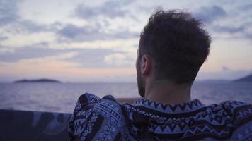 réfléchi homme à la recherche à le mer. le Jeune homme qui fournit transport dans le mer est à la recherche à le mer de le bateau. video