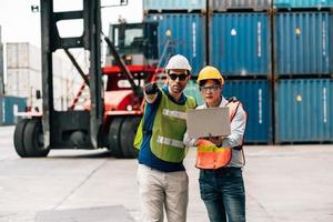 Team Engineer and worker wear safety uniform check control loading freight cargo container use computer laptop at commercial dock warehouse,transportation import,export logistic industrial service photo