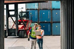 Team Engineer and worker wear safety uniform check control loading freight cargo container use computer laptop at commercial dock warehouse,transportation import,export logistic industrial service photo