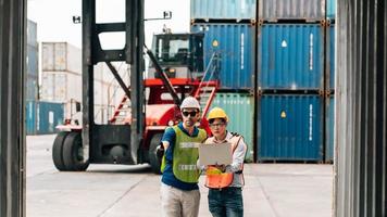 Team Engineer and worker wear safety uniform check control loading freight cargo container use computer laptop at commercial dock warehouse,transportation import,export logistic industrial service photo