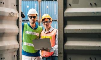 Team Engineer and worker wear safety uniform check control loading freight cargo container use computer laptop at commercial dock warehouse,transportation import,export logistic industrial service photo