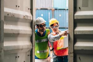 Team Engineer and worker wear safety uniform check control loading freight cargo container use computer laptop at commercial dock warehouse,transportation import,export logistic industrial service photo