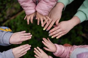 Close up of hands and fingers of mother with kids in spring forest background. photo