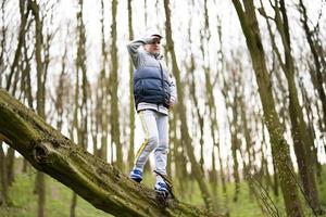 Boy climbed a felled tree in spring forest. Happy childhood moments. photo