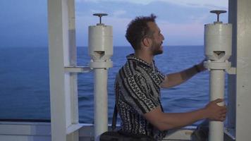 The adventurous teenager is on the road. Young man sitting on the ferry watching the sea. video