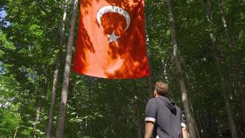 il giovane uomo guardare a il Turco bandiera. il giovane uomo sembra a il Turco bandiera con grande ammirazione e saluta il bandiera. video