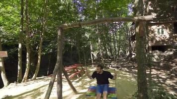 Swinging on a swing in slow motion. Young man swinging on a swing in the forest. video