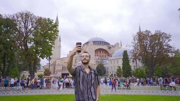 The man taking a photo with the phone. The young man is taking a selfie with his phone while walking around the historical places of Istanbul. video