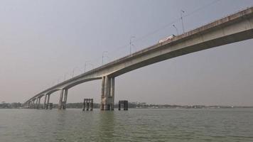 Going through a river with a water vessel and under a big bridge. Crossing from under a river bridge with a trawler. Beautiful natural river footage with a bridge and vehicles moving on the bridge. video