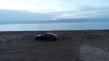 un negro coche en el mar playa a puesta de sol video