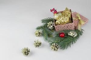 pink box with golden christmas balls, green christmas tree branches and golden cones photo