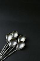 five vintage silver teaspoons on black background photo