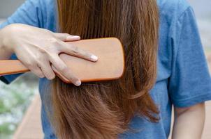 Blonde haired Asian woman posing front combing her hair photo