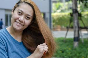 Blonde haired young beautiful Asian woman posing combing her hair photo