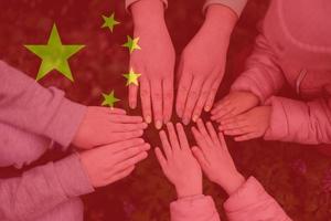 Hands of kids on background of China flag. Chinese patriotism and unity concept. photo