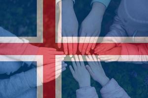Hands of kids on background of Iceland flag. Icelander patriotism and unity concept. photo