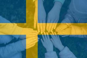 Hands of kids on background of Sweden flag. Swedish patriotism and unity concept. photo