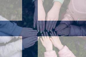 Hands of kids on background of Finland flag. Finnish patriotism and unity concept. photo