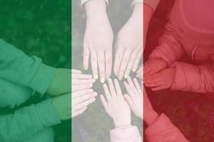 Hands of kids on background of Italy flag. Italian patriotism and unity concept. photo