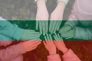 Hands of kids on background of Bulgaria flag. Bulgarian patriotism and unity concept. photo