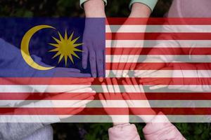 Hands of kids on background of Malaysia flag. Malaysian patriotism and unity concept. photo