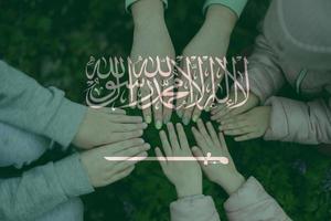 Hands of kids on background of Saudi Arabia flag. Saudi Arabian patriotism and unity concept. photo