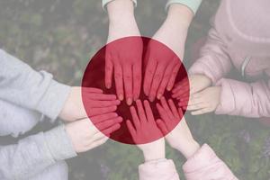 Hands of kids on background of Japan flag. Japanese patriotism and unity concept. photo