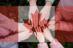 Hands of kids on background of Canada flag. Canadian patriotism and unity concept. photo