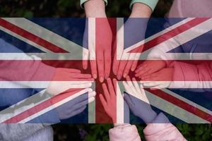 Hands of kids on background of United Kingdom flag. British patriotism and unity concept. photo