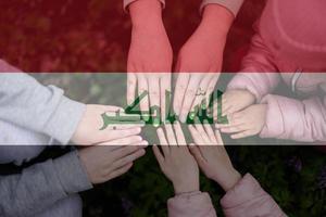 Hands of kids on background of Iraq flag. Iraqi patriotism and unity concept. photo