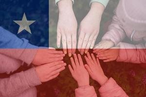 Hands of kids on background of Chile flag. Chilean patriotism and unity concept. photo