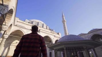 historisk moské med fyra minareter. muslim ung man kommer till de moské till be. video