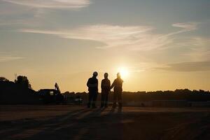 Silhouettes of engineers at construction site at sunset. photo