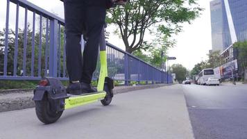 hombre en formal traje montando eléctrico scooter en el ciudad. hombre en formal traje unidades eléctrico scooter en el ciudad. ambientalmente simpático empresario. video