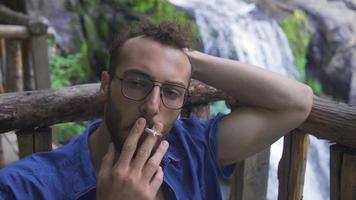 betont Mann ist Rauchen. Rauchen Sucht. frustriert süchtig jung Mann Rauchen im Wald. video