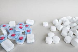 White pressed salt tablets and colored dishwasher capsules close-up. Place for text photo