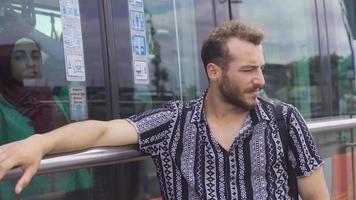 malheureux et ennuyé Jeune homme. malheureux et ennuyé Jeune homme dans le ville et le tram qui passe par dans le Contexte. video