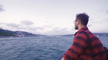 Free man on the ferry in the Bosphorus. The free man on the ferry opens his hands and watches the cityscape. video