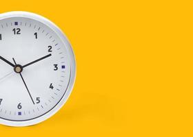 A white circular alarm clock on a bright yellow background wall in pastel colors. minimal creative concept. And copy space for your text. minimal concept idea photo