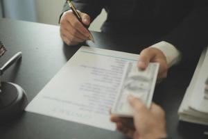 concepto de justicia y derecho. El asesor legal presenta al cliente un contrato firmado con mazo y derecho legal o una reunión de equipo legal en el bufete de abogados en segundo plano. foto