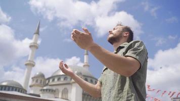 jung Muslim beten. jung Muslim öffnet seine Hände und betet im das Hof von das Moschee. video