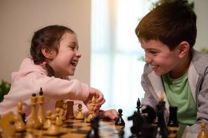 Kids having great time together playing chess. Chess game for clever mind. Logic development, leisure board games, entertainment, intelligent hobby and education concept photo