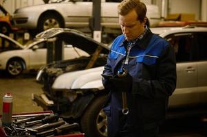 Technician, mechanic in professional uniform with wrench at repair shop. Automobile warranty repair and maintenance concept photo