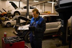 Automobile warranty repair and maintenance concept. Technician, mechanic in professional uniform with wrench at repair shop. photo