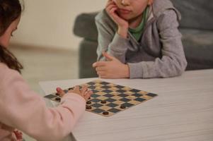 Handsome school aged kids playing checkers table game, staying at home Quarantine concept. Board game and kids leisure concept. Family time. photo