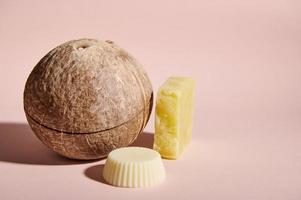 Still life. Coconut and homemade natural organic bar of soap or solid dry shampoo and hair conditioner, isolated on pink photo