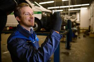 Auto mechanic picks up a nut while servicing a car in a car workshop. Car maintenance and auto service concept photo