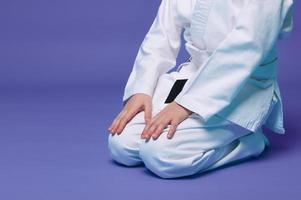 Cropped view of an aikido fighter in a white kimono during the practice of oriental martial arts, isolated over purple background with copy ad space photo