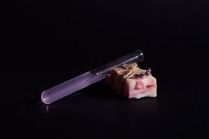 Still life Purple lavender extract in laboratory test tube and a bar of pink soap with lavender flower isolated on black photo